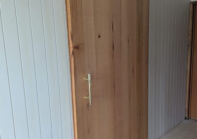 Custom wooden sliding barn door installed indoors for outdoor access.