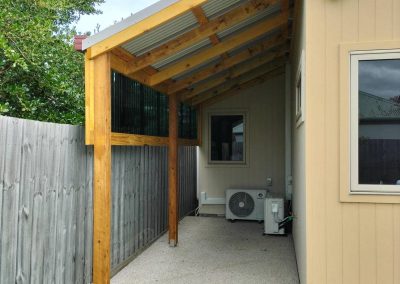 Outdoor covered patio with timber frame and corrugated roofing, ideal for outdoor living spaces.
